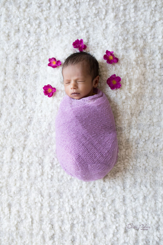 Handsome newborn boy with purple flowers 