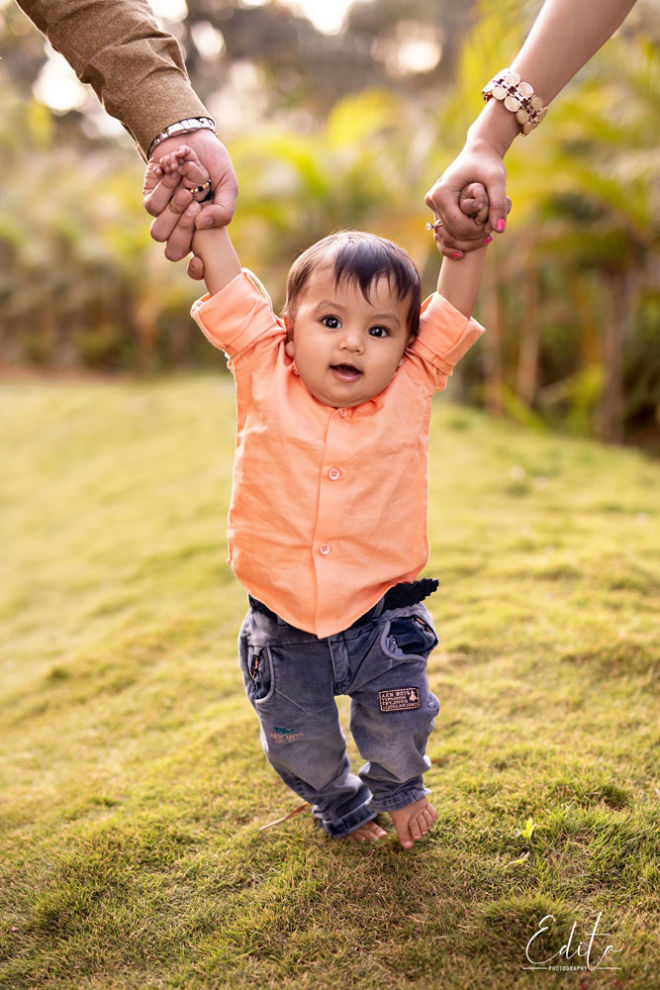 Outdoor baby photoshoot Pune, baby boy is holding parents hands and walking
