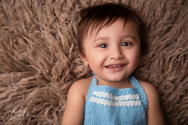 Smiling baby boy on brown flokati in photo studio Pune