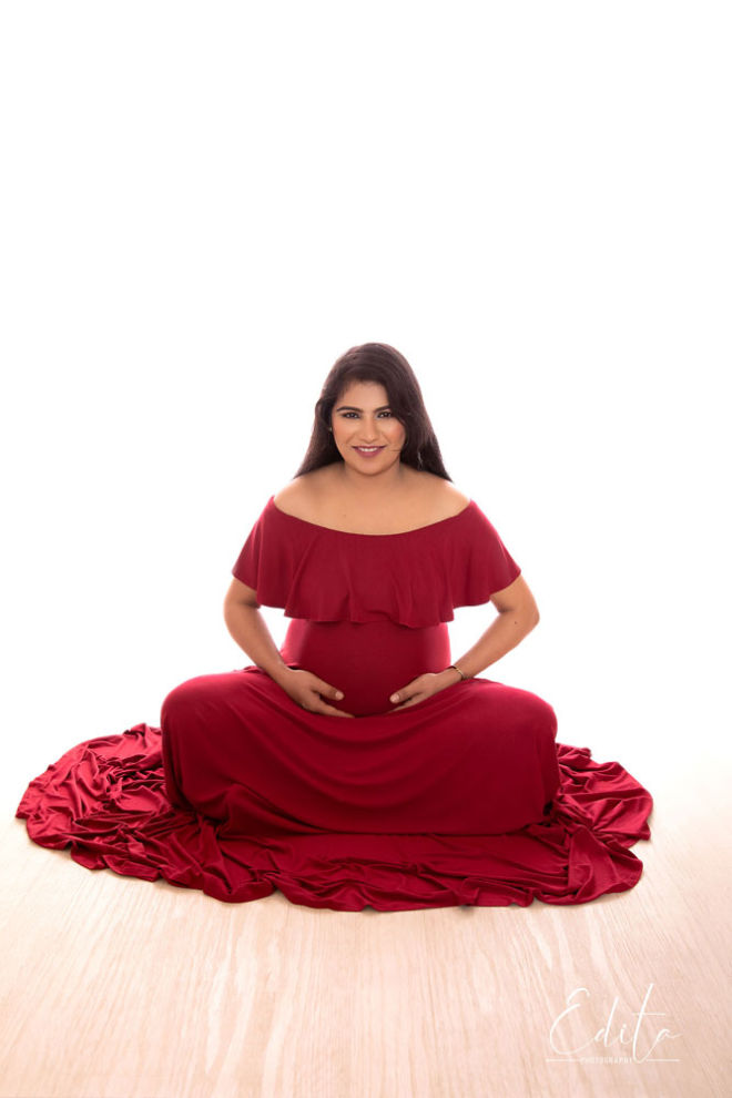 Backlit pregnancy sitting red gown photo