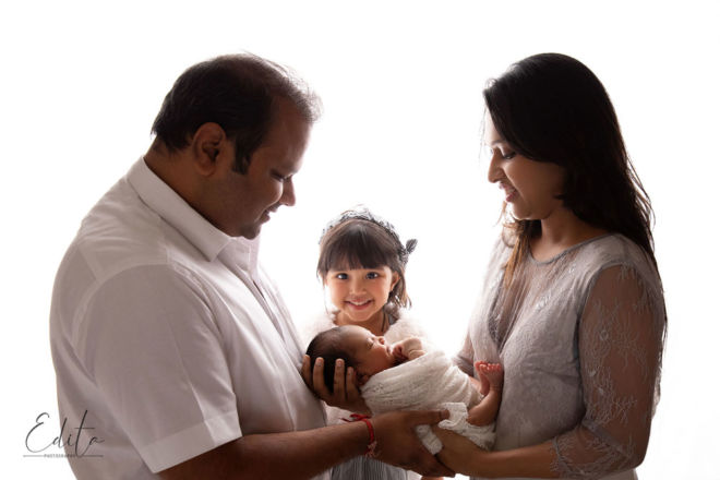 Backlit family of 4 portrait with newborn baby