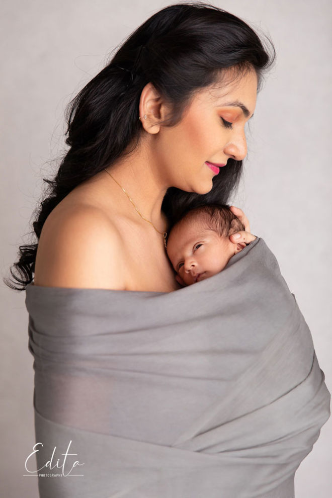Newborn baby with mother wrapped in grey fabric together
