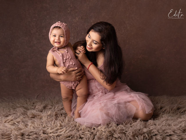 Mummy and her daughter in pink outfits on brown background