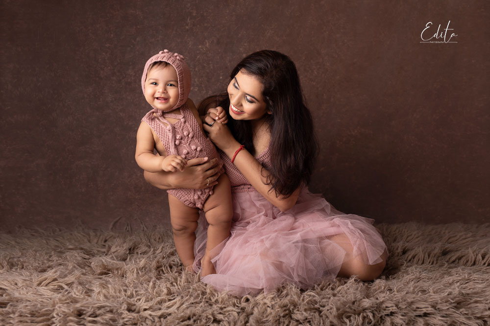 Mummy and her daughter in pink outfits on brown background. Mothers day