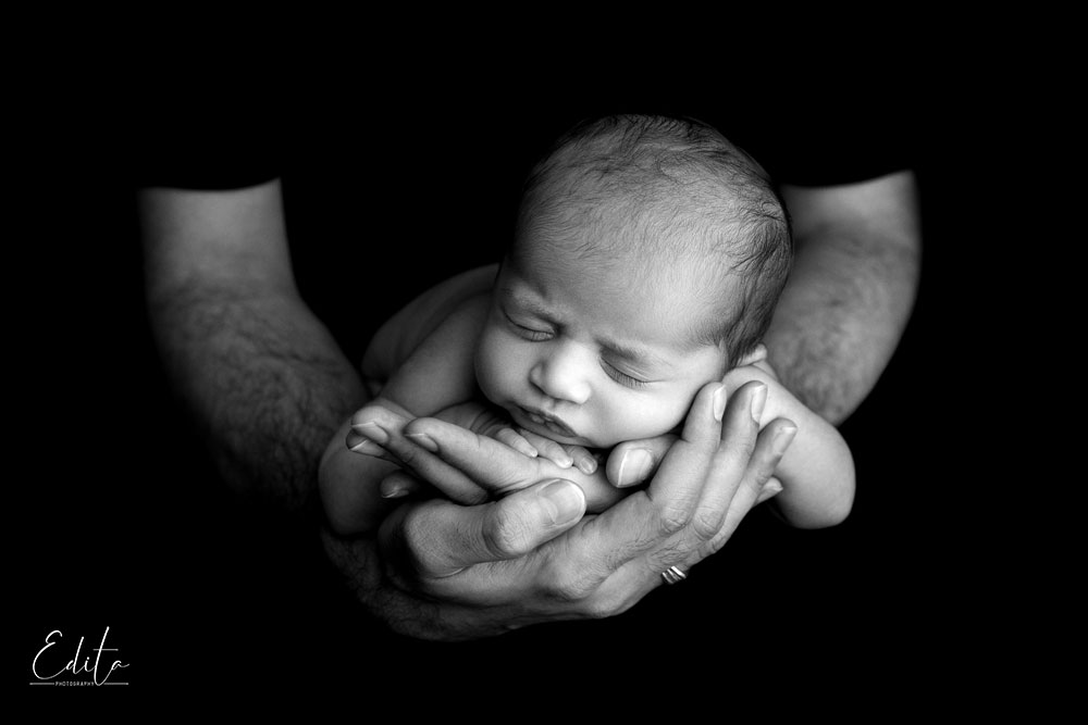Newborn girl in father hands black and white photo
