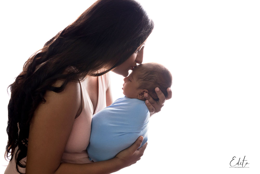 Backlit mother kissing her newborn son photography in Pune