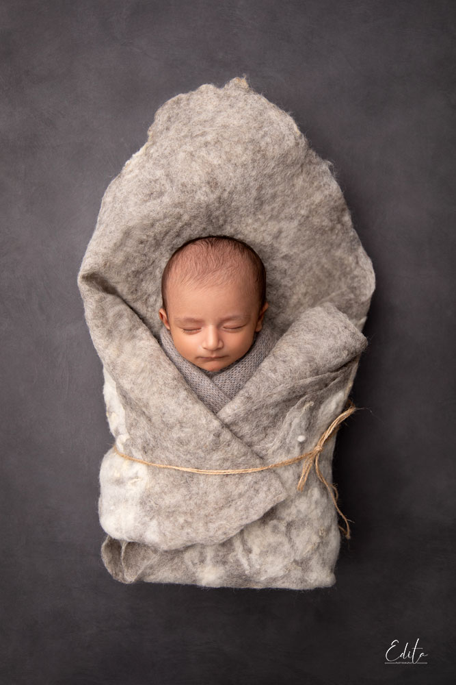 Handsome newborn baby wrapped in grey wool