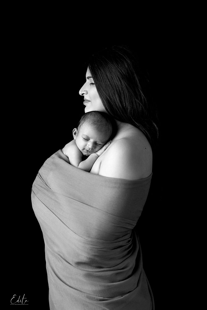 Mother wrapped in fabric with newborn baby