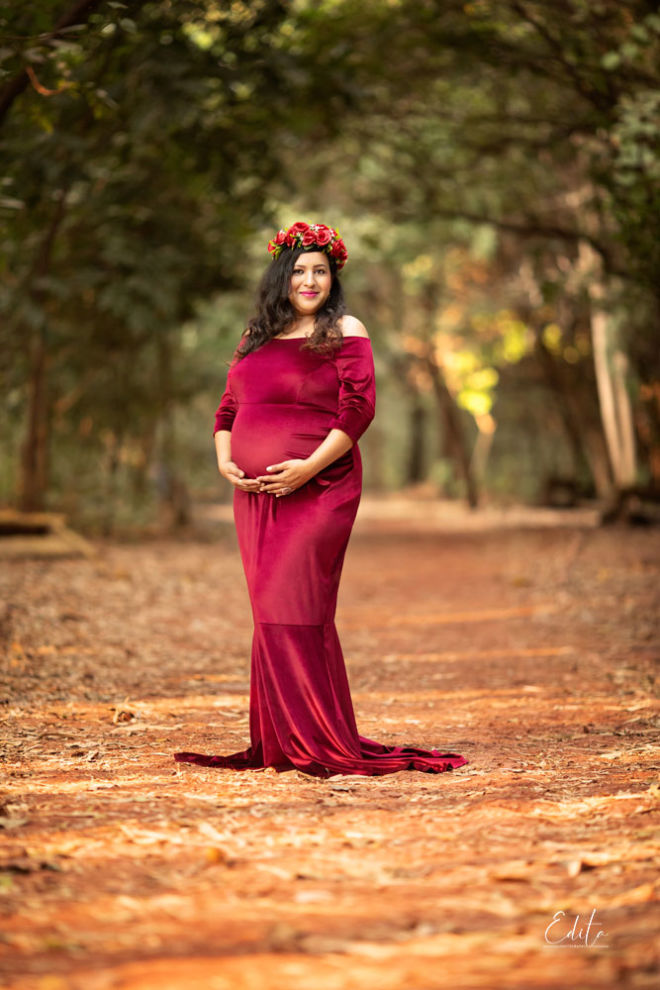 Maternity photo shoot in maroon velvet gown in forest near Pune