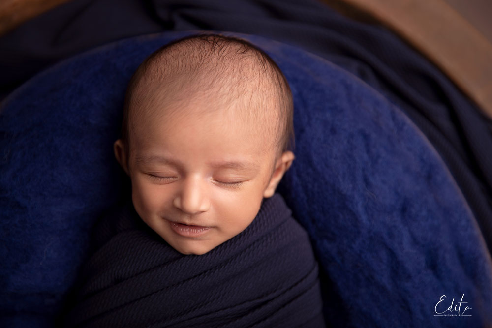 Smiling newborn baby in navy blue