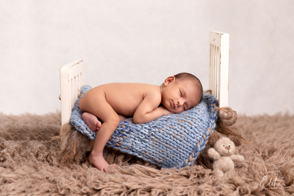 Newborn baby posed on tiny bed prop