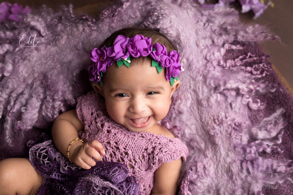 3 month old baby girl in purple setup with headband and big smile