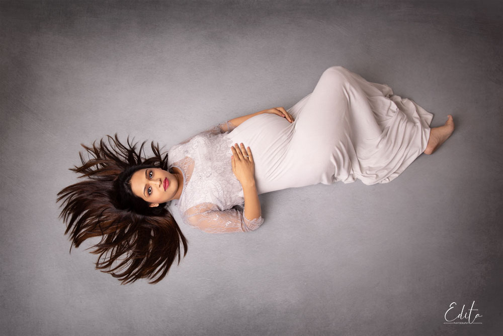 Mother to be aerial photo in light grey gown. 2nd time parents maternity photoshoot