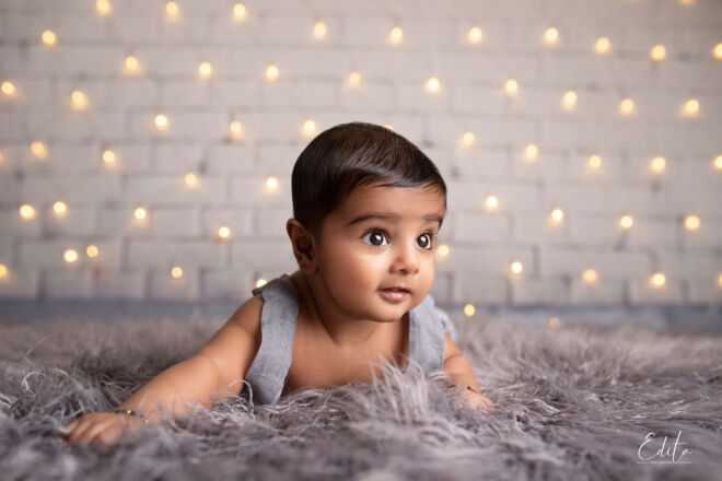 Baby photo shoot on tummy with Christmas lights in background