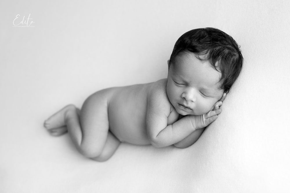 Newborn boy side pose on bean bag black and white